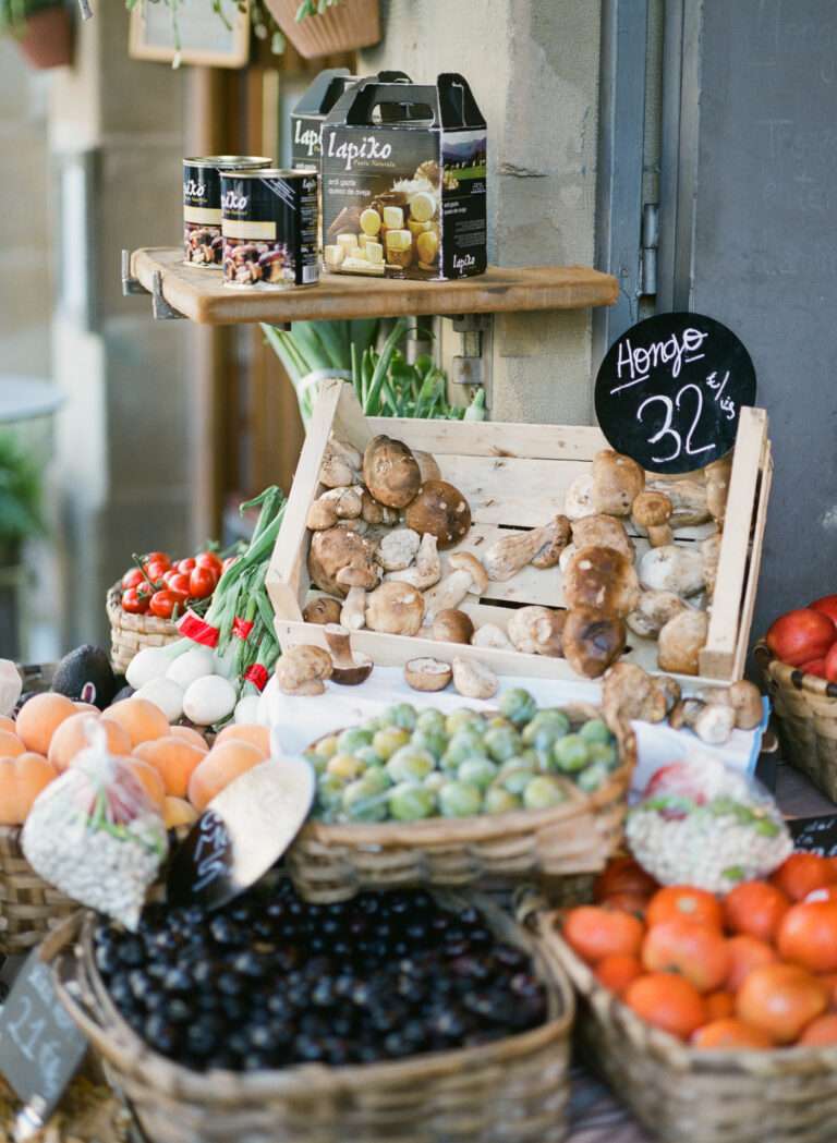 A market stand in San Sebastian, Spain showing fresh cep mushrooms, tomatoes, olives, and other vegetables, 2018